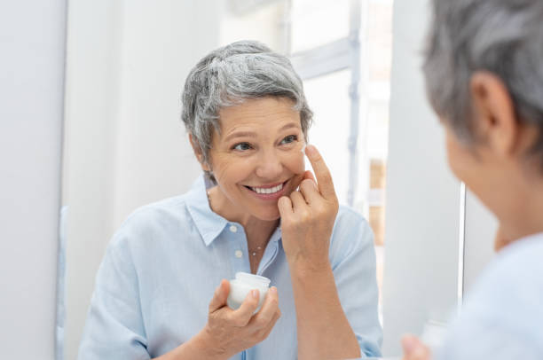 ältere frau, die anwendung von anti-aging-creme - human face mature women make up women stock-fotos und bilder