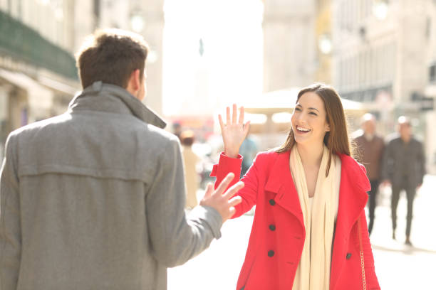 Happy friends meeting and greeting in the street Two happy friends meeting and greeting in the street of a big city waving gesture stock pictures, royalty-free photos & images