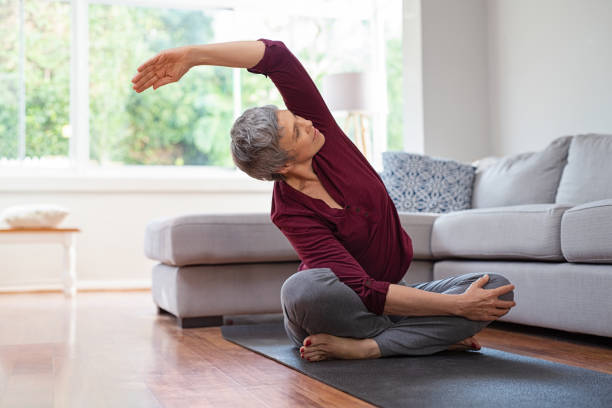 reife frau in yoga-pose - arm extended stock-fotos und bilder