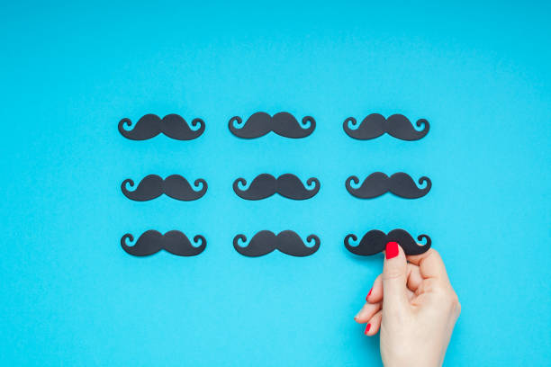 Paper moustaches for men fathers dad concept Creative flatlay overhead top view retro stylish black paper photo booth props moustaches turquoise female hand background copy space. Men health awareness month fathers day masculinity concept women movember mustache facial hair stock pictures, royalty-free photos & images