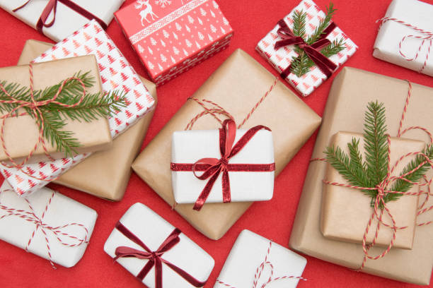 christmas presentförpackning insvept i prydnad papper och dekorativa röda rep band på röd yta. kreativ hobby, ovanifrån. laga till xmas. - julklapp bildbanksfoton och bilder