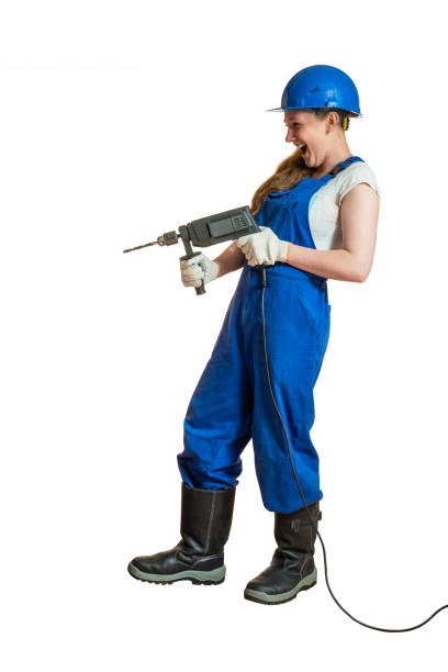 istock Girl in overalls with a drill in her hands. 1044188956