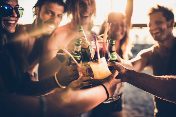 Close up of happy friends toasting with alcohol at sunset. Close up of happy people having fun on a party while toasting with alcohol. beach bar stock pictures, royalty-free photos & images