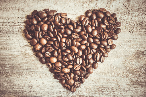 Heart shaped coffee beans on brown paper background.