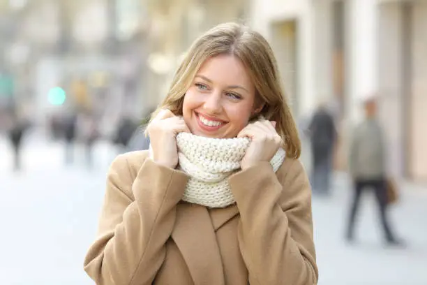 Happy woman warmly clothed looking a side in winter walking in the street