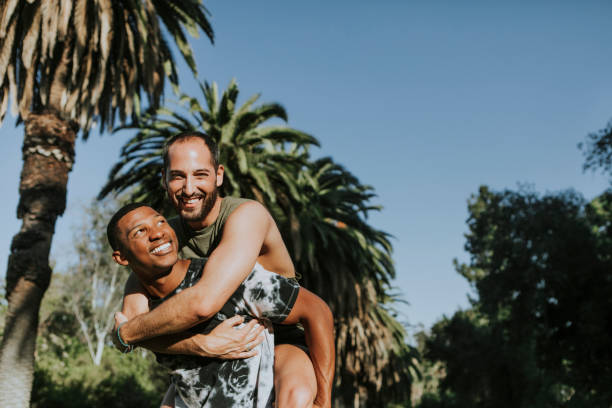 coppia gay che si abbraccia nel parco - homosexual homosexual couple black ethnic foto e immagini stock