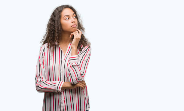 istock Beautiful young hispanic woman with hand on chin thinking about question, pensive expression. Smiling with thoughtful face. Doubt concept. 1044207282