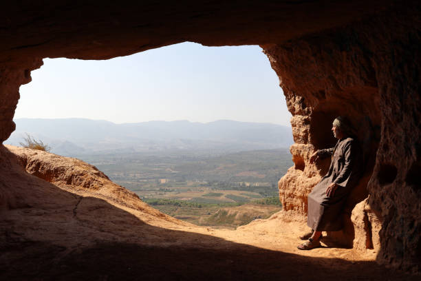 hermit sitting at the entrance of a cave - hermit imagens e fotografias de stock