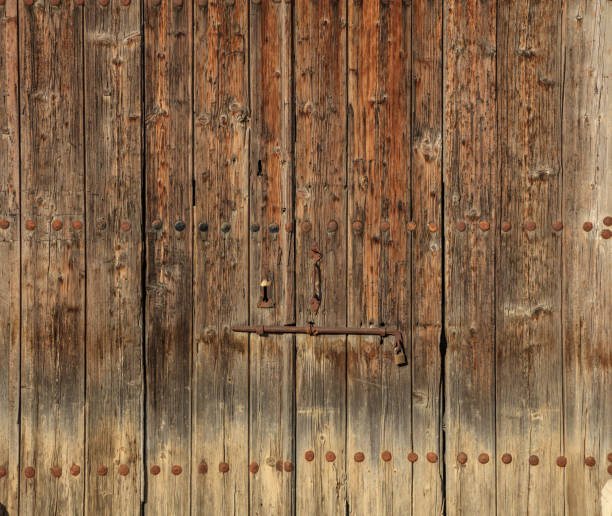 istock Wooden brown timeworn door. Space for text backdrop, rusty latch and padlock. Closeup view, details. 1044211398
