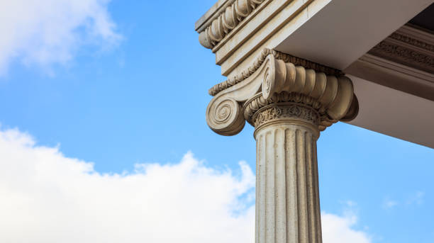 istock Marble pillar detail. Ancient ionic column of white ornate marble. Blue sky, under, close up view, banner 1044211510