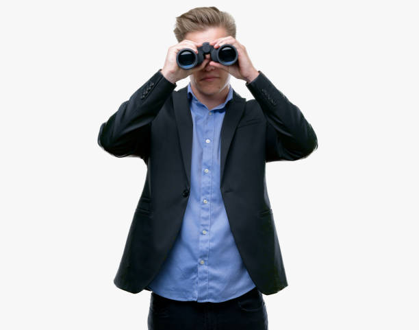 istock Young handsome blond man looking through binoculars with a confident expression on smart face thinking serious 1044213000