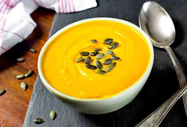 Hokkaido or butternut pumpkin soup with curry and seeds. Delicious autumn dish, top view.