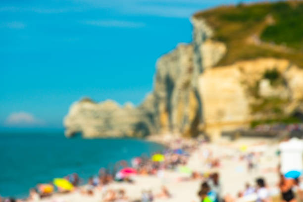Blurred image of summer beach with seashore, people and mountain cliffs
