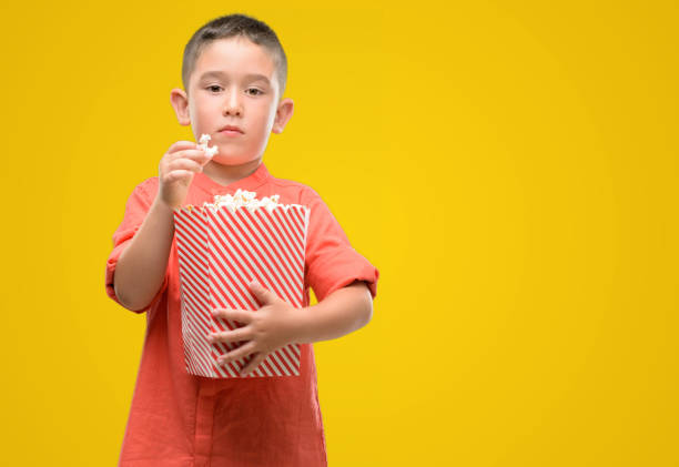 istock Dark haired little child eating popcorn with a confident expression on smart face thinking serious 1044222886