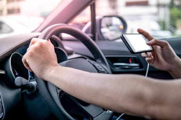 istock Male driver hand holding on steering wheel using smartphone for GPS navigation. Mobile phone mounting with magnet on the car console in modern car. Urban driving lifestyle with mobile app technology 1044223944