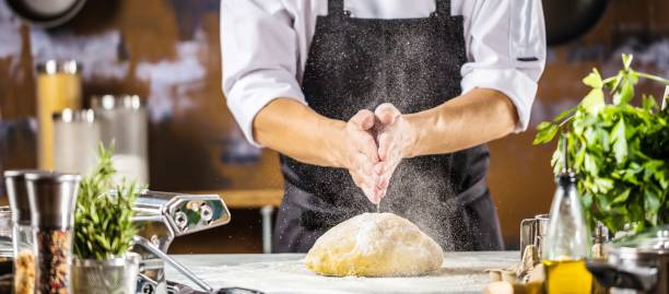 mężczyzna kucharz kucharz przygotowanie ciasta do pizzy lub makaronu na stole - makes the dough zdjęcia i obrazy z banku zdjęć