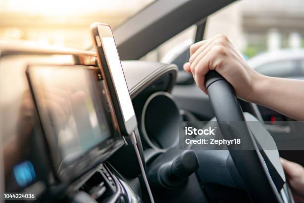 Male Driver Hand Holding On Steering Wheel Using Smartphone For Gps Navigation Mobile Phone Mounting With Magnet On The Car Console In Modern Car Urban Driving Lifestyle With Mobile App Technology Stock Photo - Download Image Now