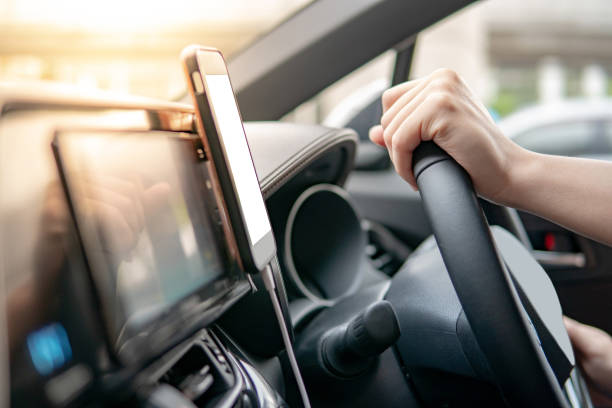 male driver hand holding on steering wheel using smartphone for gps navigation. mobile phone mounting with magnet on the car console in modern car. urban driving lifestyle with mobile app technology - map cartography travel human hand imagens e fotografias de stock