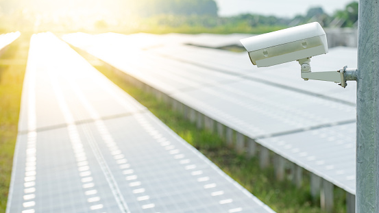 CCTV camera monitoring solar panels or polycrystalline silicon solar cells in the farm. Security in solar power plant. Photovoltaic modules for renewable energy