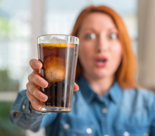 istock Redhead woman holding soda refreshment scared in shock with a surprise face, afraid and excited with fear expression 1044224362