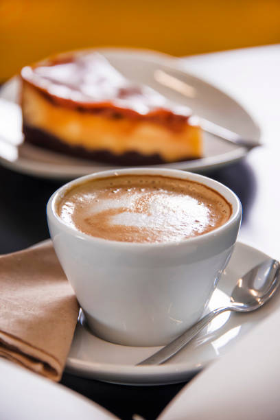 Caramel cheesecake with cappuccino and magazines. Business meal conception.