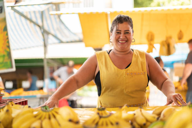 porträt von zuversichtlich besitzer - verkauf von bananen am bauernmarkt - markthändler stock-fotos und bilder