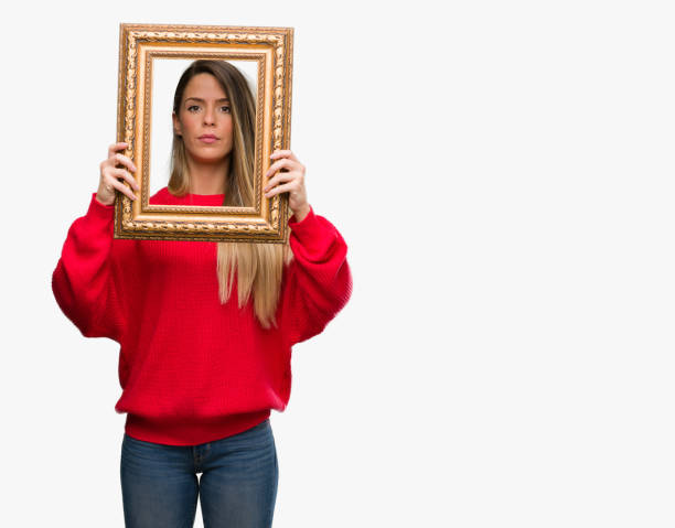 istock Beautiful young woman holding vintage frame with a confident expression on smart face thinking serious 1044233336