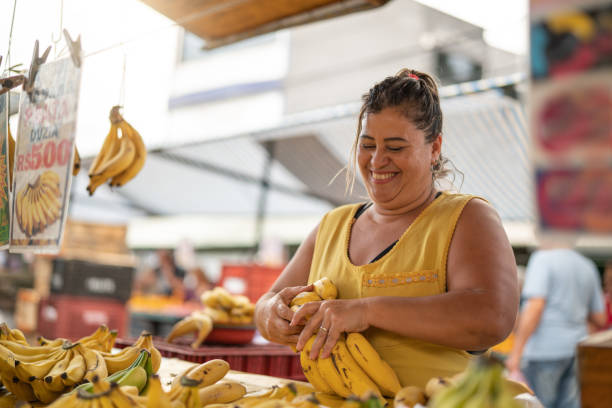 porträt von zuversichtlich besitzer - verkauf von bananen am bauernmarkt - markthändler stock-fotos und bilder