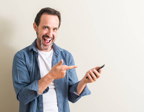 istock Senior man using smartphone very happy pointing with hand and finger to the side 1044246580