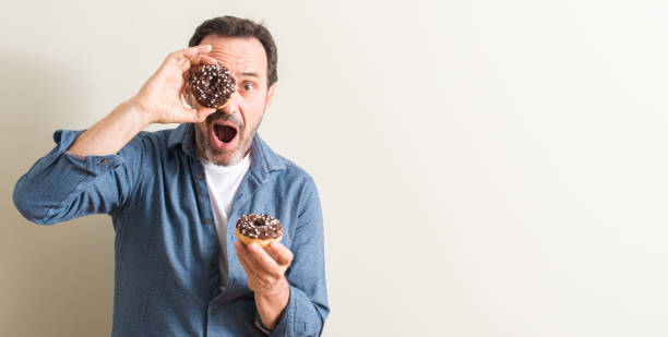 istock Senior man eating chocolate donut scared in shock with a surprise face, afraid and excited with fear expression 1044247456