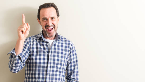 istock Senior man surprised with an idea or question pointing finger with happy face, number one 1044247574