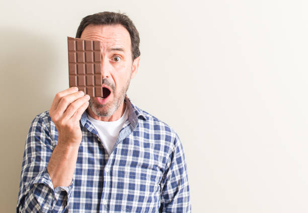 istock Senior man eating chocolate bar scared in shock with a surprise face, afraid and excited with fear expression 1044247846