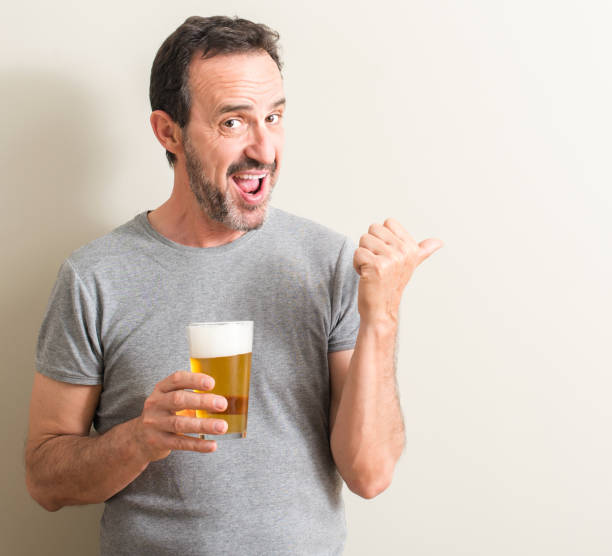 istock Senior man drinking beer pointing with hand and finger up with happy face smiling 1044253300
