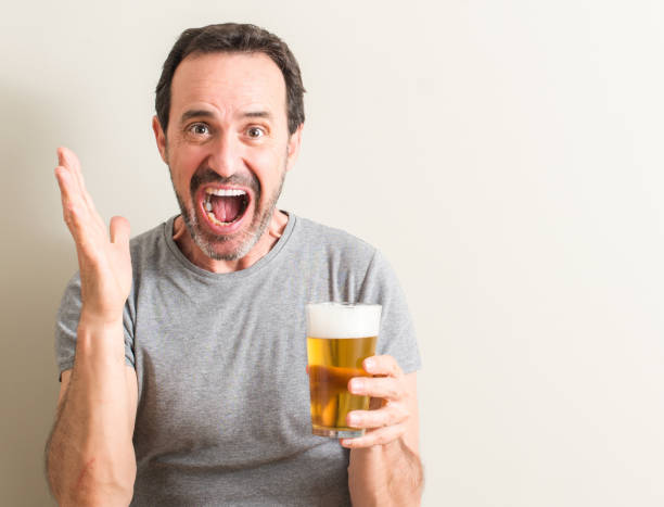 istock Senior man drinking beer very happy and excited, winner expression celebrating victory screaming with big smile and raised hands 1044253320