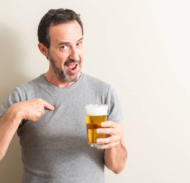 istock Senior man drinking beer with surprise face pointing finger to himself 1044253430