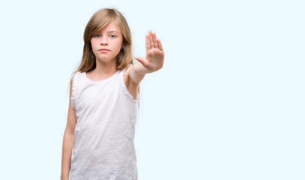 istock Young blonde toddler with open hand doing stop sign with serious and confident expression, defense gesture 1044253714