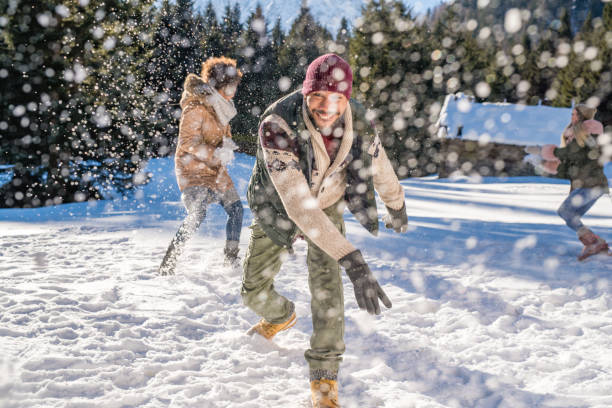 istock Man throwing snowball into air while having fun with his friends 1044253862