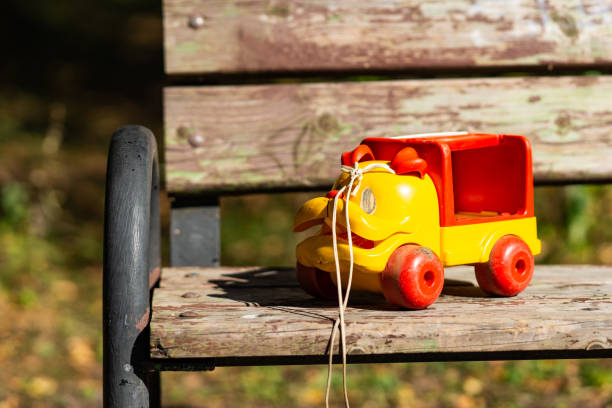 istock Funny yellow plastic toy car on a park bench 1044253982