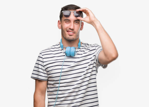 istock Handsome young man wearing headphones winking looking at the camera with sexy expression, cheerful and happy face. 1044257722