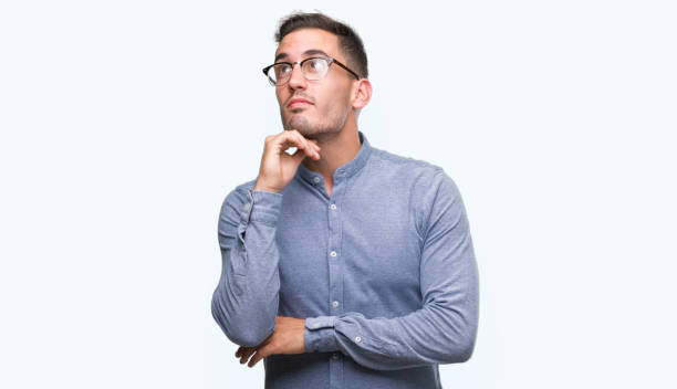 istock Handsome young elegant man wearing glasses with hand on chin thinking about question, pensive expression. Smiling with thoughtful face. Doubt concept. 1044257964