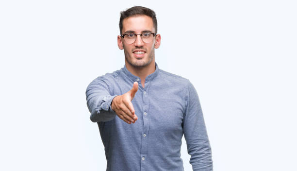 istock Handsome young elegant man wearing glasses smiling friendly offering handshake as greeting and welcoming. Successful business. 1044258172