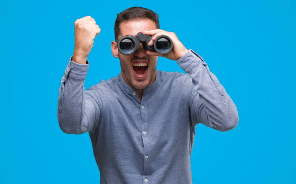 istock Handsome young man looking through binoculars annoyed and frustrated shouting with anger, crazy and yelling with raised hand, anger concept 1044258276