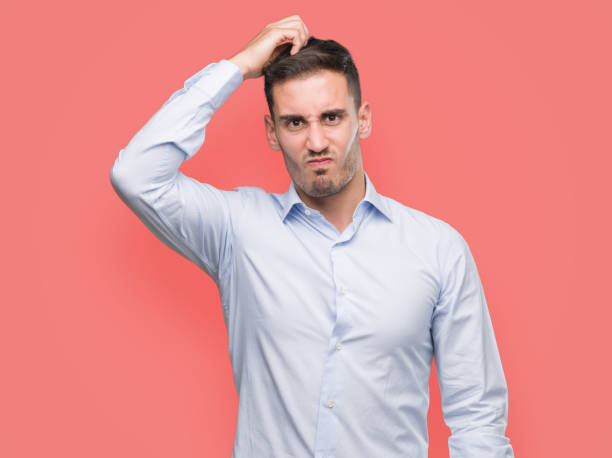 istock Handsome young businessman confuse and wonder about question. Uncertain with doubt, thinking with hand on head. Pensive concept. 1044259334