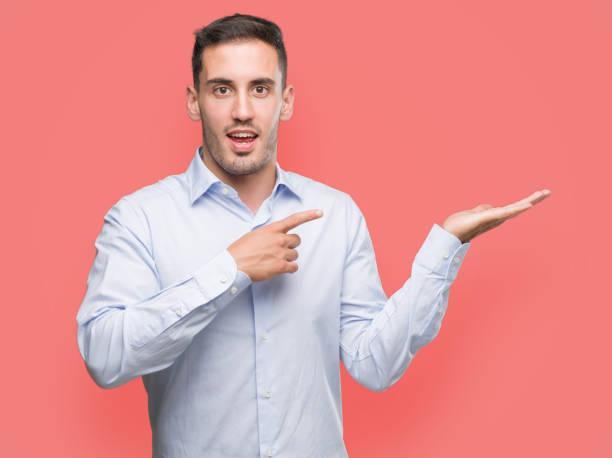 istock Handsome young businessman amazed and smiling to the camera while presenting with hand and pointing with finger. 1044259464
