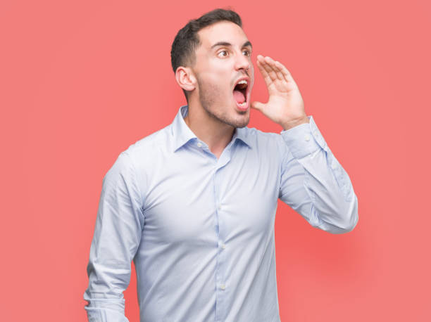 bonito jovem empresário gritando e gritando alto a lado com a mão na boca. conceito de comunicação. - men shouting human hand sound - fotografias e filmes do acervo