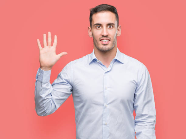 istock Handsome young businessman showing and pointing up with fingers number five while smiling confident and happy. 1044261614
