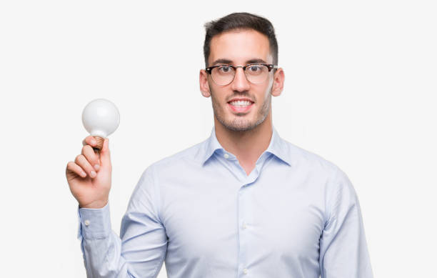 istock Handsome young man holding lightbulb as idea with a happy face standing and smiling with a confident smile showing teeth 1044261784