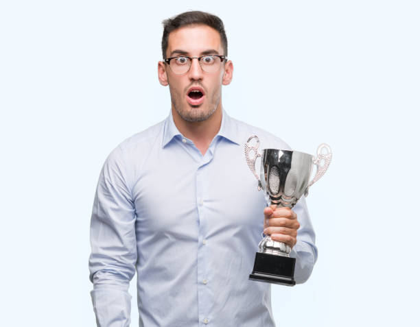 istock Handsome young man holding trophy scared in shock with a surprise face, afraid and excited with fear expression 1044261900