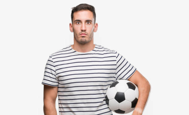 istock Handsome young man holding soccer football with a confident expression on smart face thinking serious 1044262780