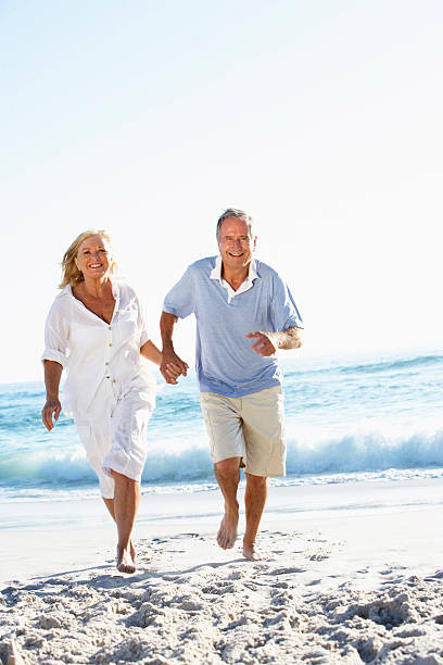 istock Senior Couple Running Along Beach 104426574